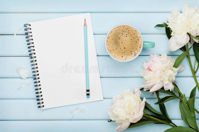 la-tasse-de-café-de-matin-le-carnet-vide-le-crayon-et-la-pivoine-blanche-fleurit-sur-la-table-en-bois-bleue-petit-déjeuner-73031139