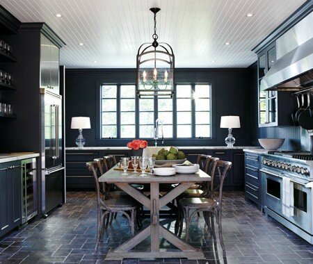 house and home dark black kitchen rustic farmhouse table beadboard ceiling stainless appliances pavers floor marble countertops