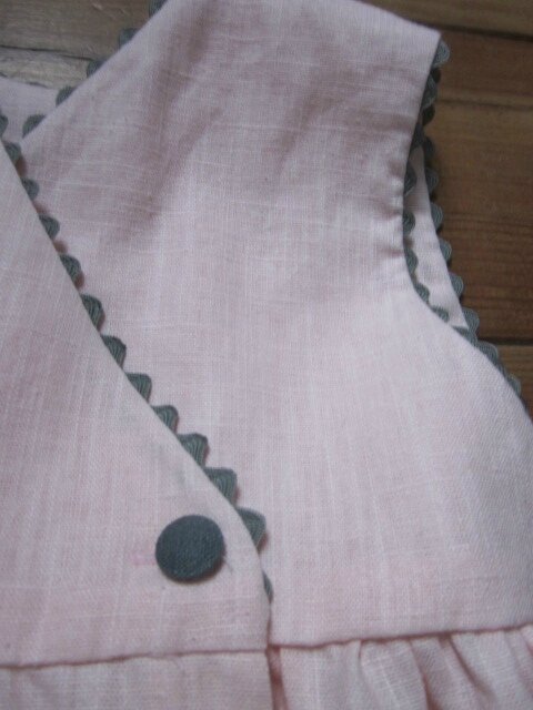 Robe FAUSTINE sans manche, portefeuille dans le dos en V fermée par 2 boutons, deux poches plaquées sur le devant, croquet aux emmanchures, à l'encolure et au bord des poches (20)