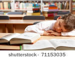 stock_photo_image_of_young_boy_sleeping_near_books_in_the_library_71153035