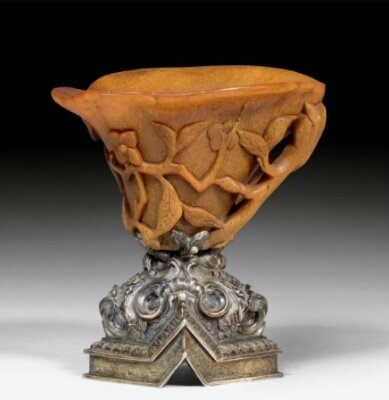 A carved rhinoceros horn libation cup with silver foot