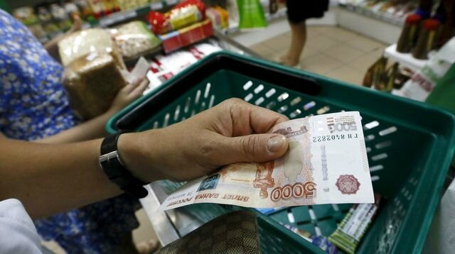 russie-crise-rouble-economie-a-customer-holds-a-russian-5-000-rouble-banknote-at-a-grocery-shop-in-krasnoyarsk_5400551