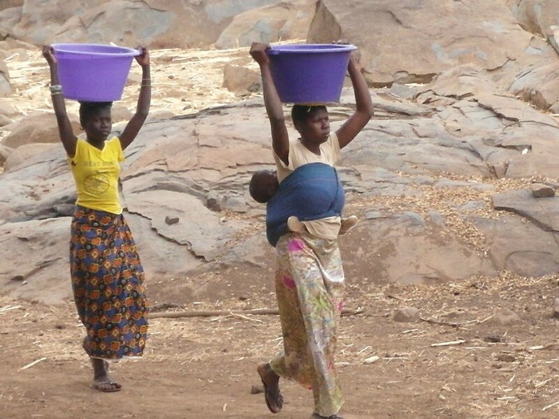 deux jeunes femmes portent des bassines d'eau du puit