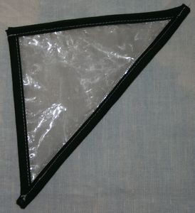 triangle fait avec un sac plastique épais doublé d'un tissus façon organda chair, le tout entouré d'un biais noir