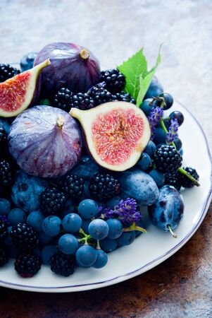 129522774-figues-biologiques-fraîches-raisins-pruneaux-et-dewberry-sur-la-plaque-sur-fond-de-bois