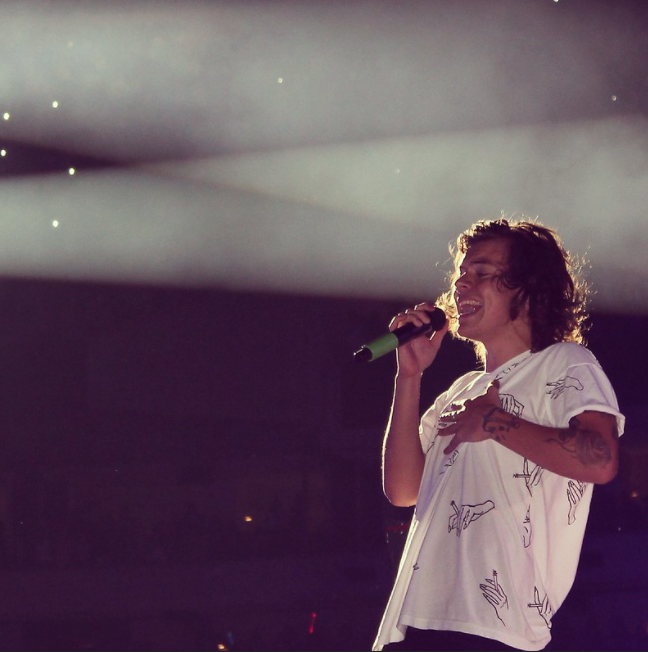 Harry Styles sur scène portant un t-shirt blanc avec des motifs de mains