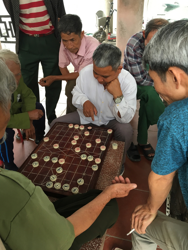 Les hommes jouent au Mahjong sur la place du village, ça semble très sérieux ! 