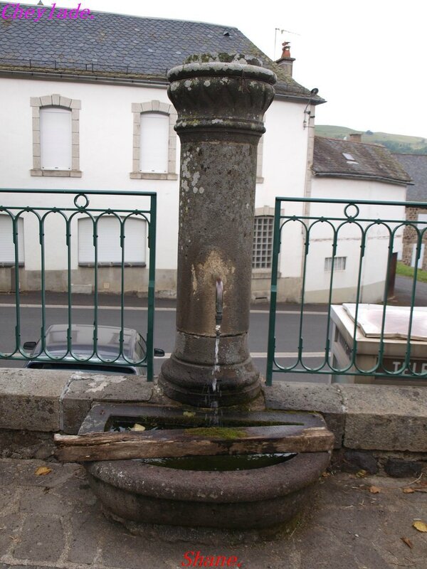 le 06 juillet 2014 fontaine au centre du village sur la D62 à Cheylade