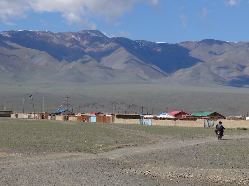 Un couple de Mongols à moto en route vers le village de Chandmani et la chaîne de l'Altaï en arrière-plan - aïmag Hovd