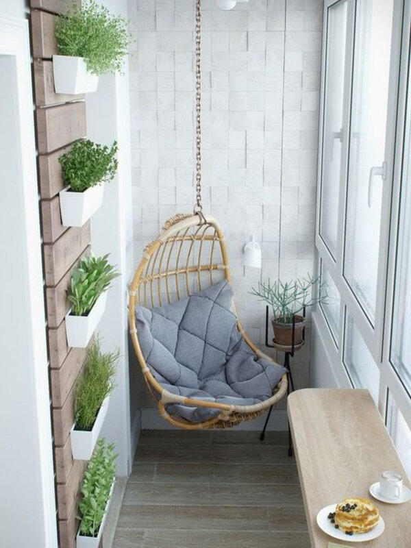 un-fauteuil-en-rotin-suspendu-dans-un-balcon-ferme-et-plantes-en-jardinieres-sur-le-mur_5891147