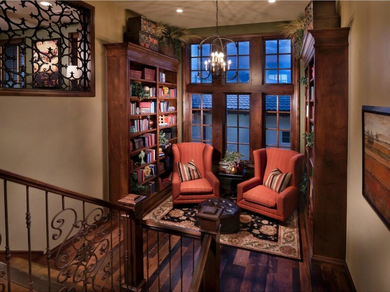 traditional-small-living-room-design-with-brown-varnishes-pine-wood-wall-library-shelves-and-classic-chandelier-over-double-orange-fabric-wingback-chairs-also-brown-round-