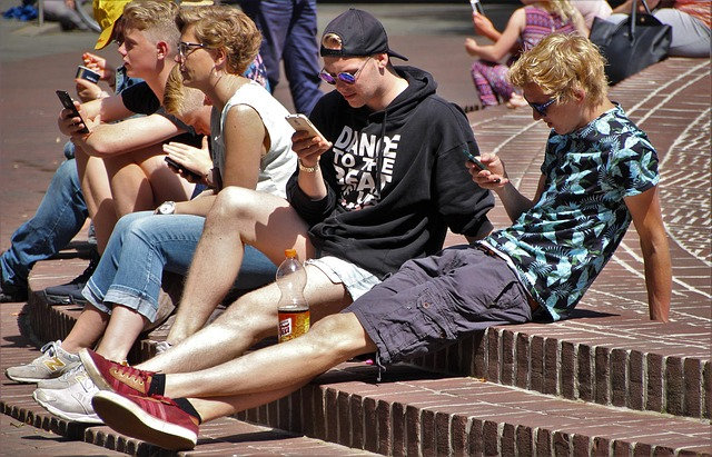 des adolescents assis sur des marches regardant leur mobile