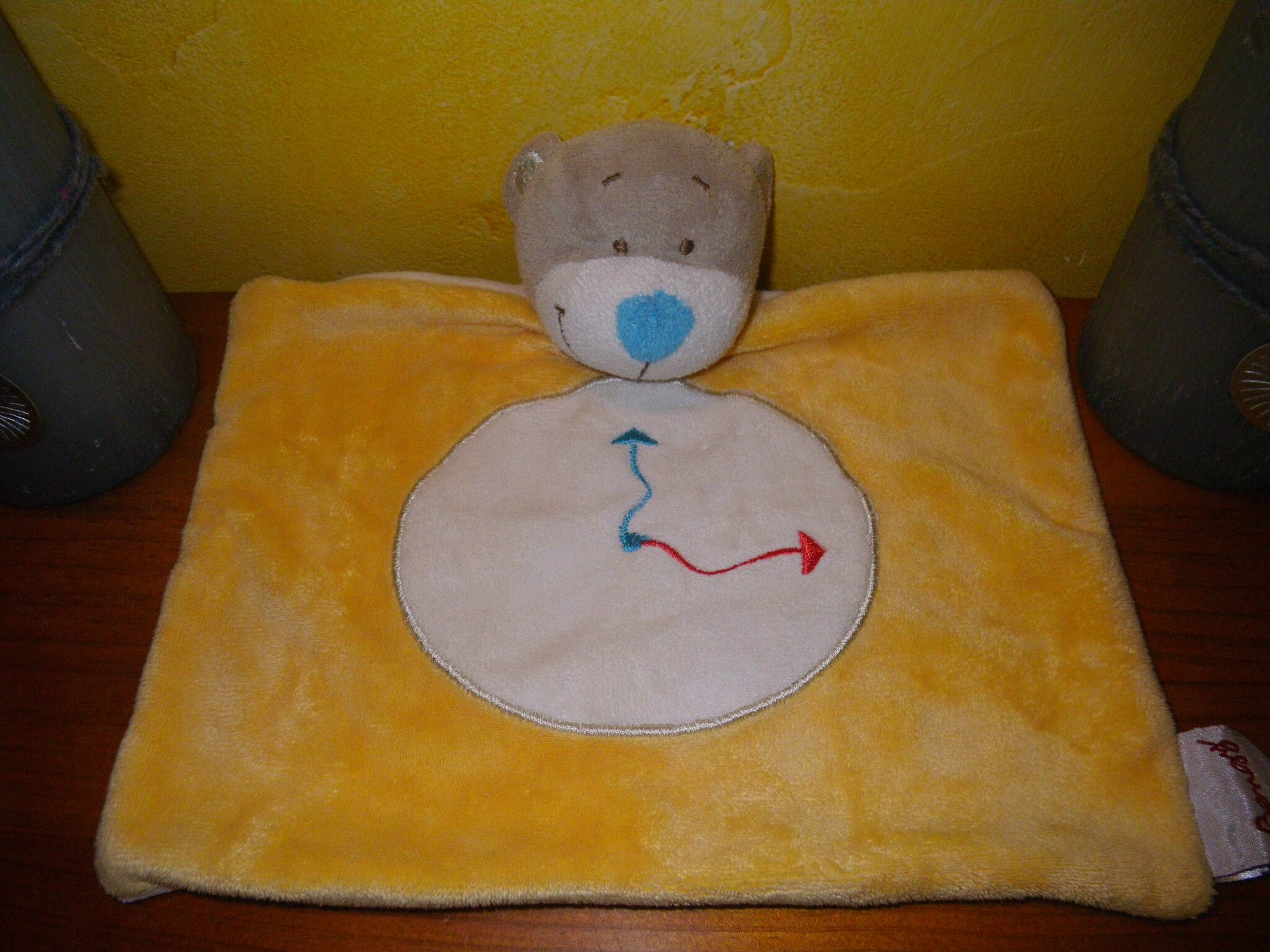 ours marque Bengy avec motif horloge. doudou plat jaune nez bleu