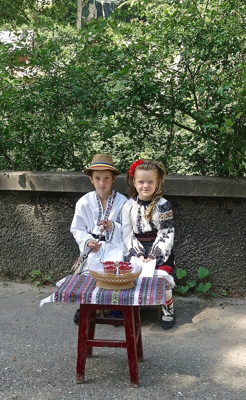 enfants en costumes traditionnels vendant des fraises des bois