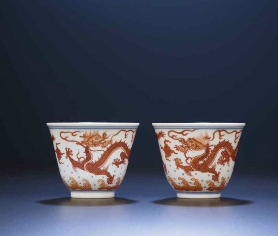 A fine and rare pair of iron-red 'dragon' wine-cups, Qianlong six-character sealmarks and of the period (1736-1795) 