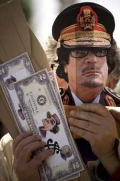 26mars11_Un_manifestant_porte_un_masque___l_effigie_du_colonel_Kadhafi_lors_d_une_manifestation_contre_les_bombardements_en_Libye___Rota_en_Espagne